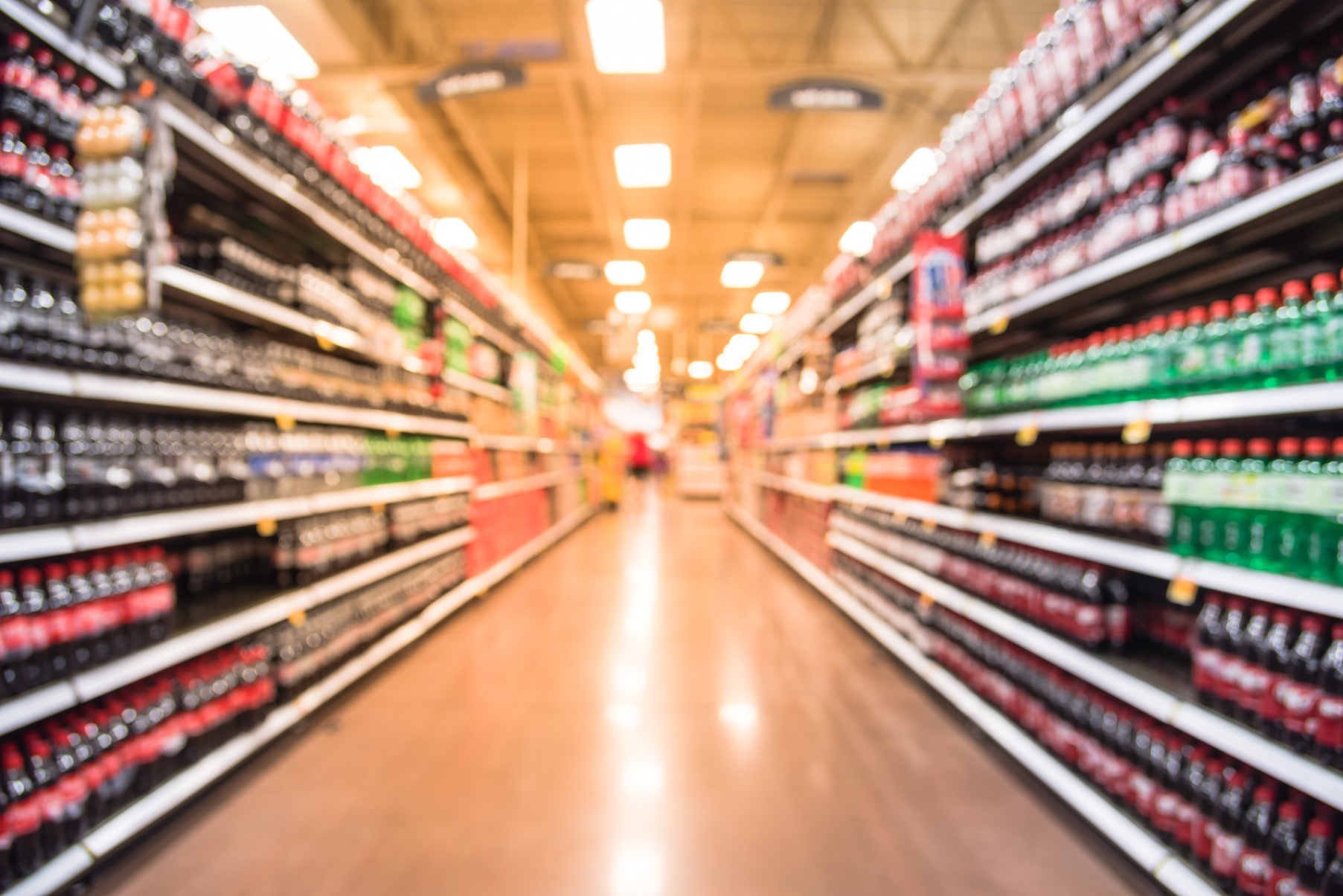 Abstract blurred soft drinks aisle with customer shopping